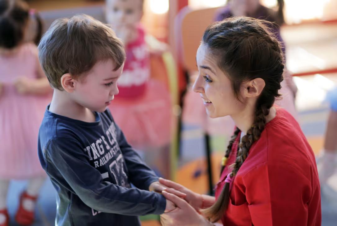 Teacher talking with a young boy in a classroom