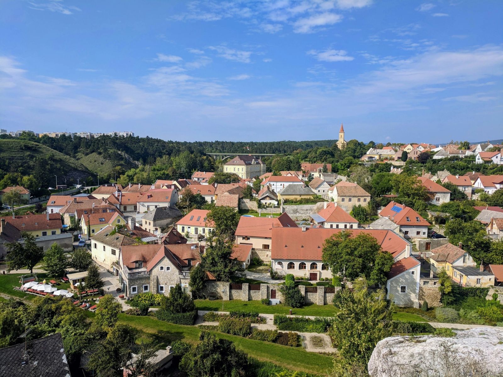 A small Central European town of red-roofed houses among green hills.