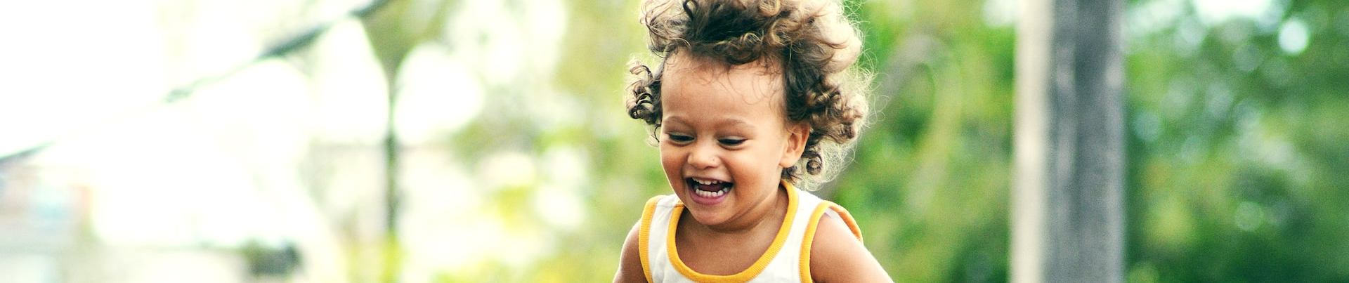 A young child laughing outdoors