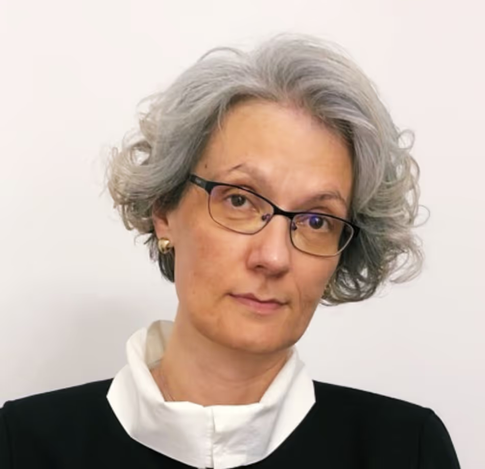Portrait of a middle-aged woman with gray curly hair, wearing glasses and a black top with a white collar.