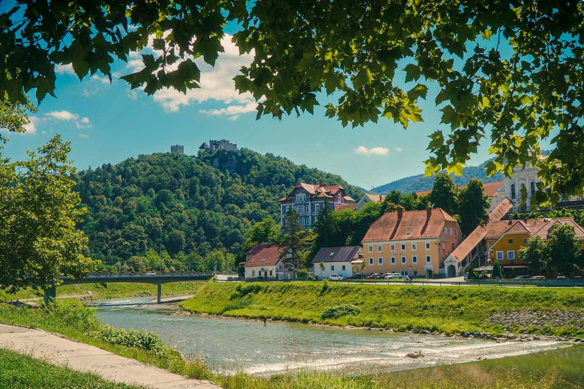 A Slovenian town above a river, surrounded by green hills.