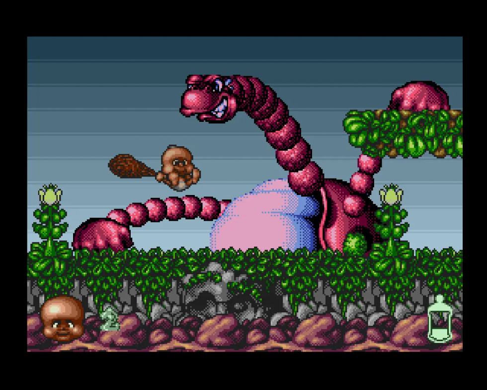 Chuck Junior affronta un enorme dinosauro rosa in Chuck Rock II: Son of Chuck per Amiga.