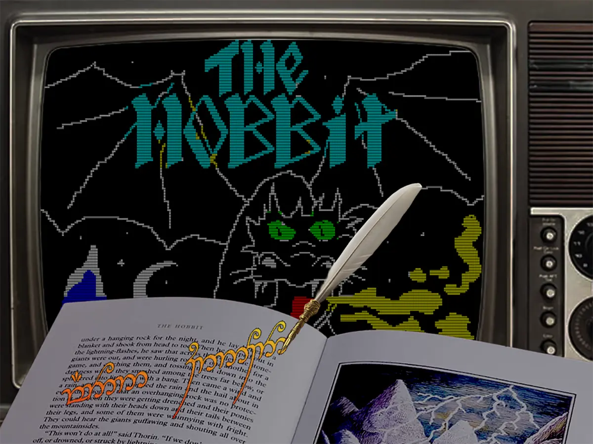Un libro aperto e una penna d’oca davanti a un monitor CRT che mostra il videogioco The Hobbit.