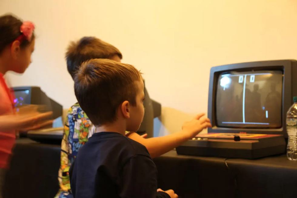 Bambini impegnati con computer e videogiochi storici al museo