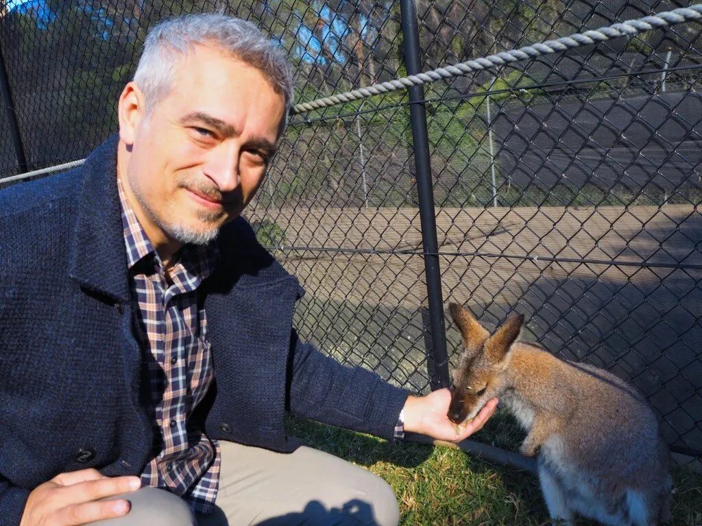 Persona seduta accanto a un canguro in un parco.