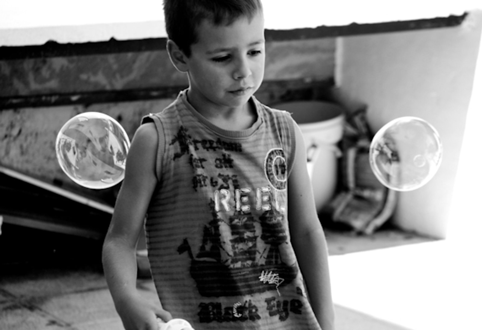 Un niño jugando con pompas de jabón, en blanco y negro