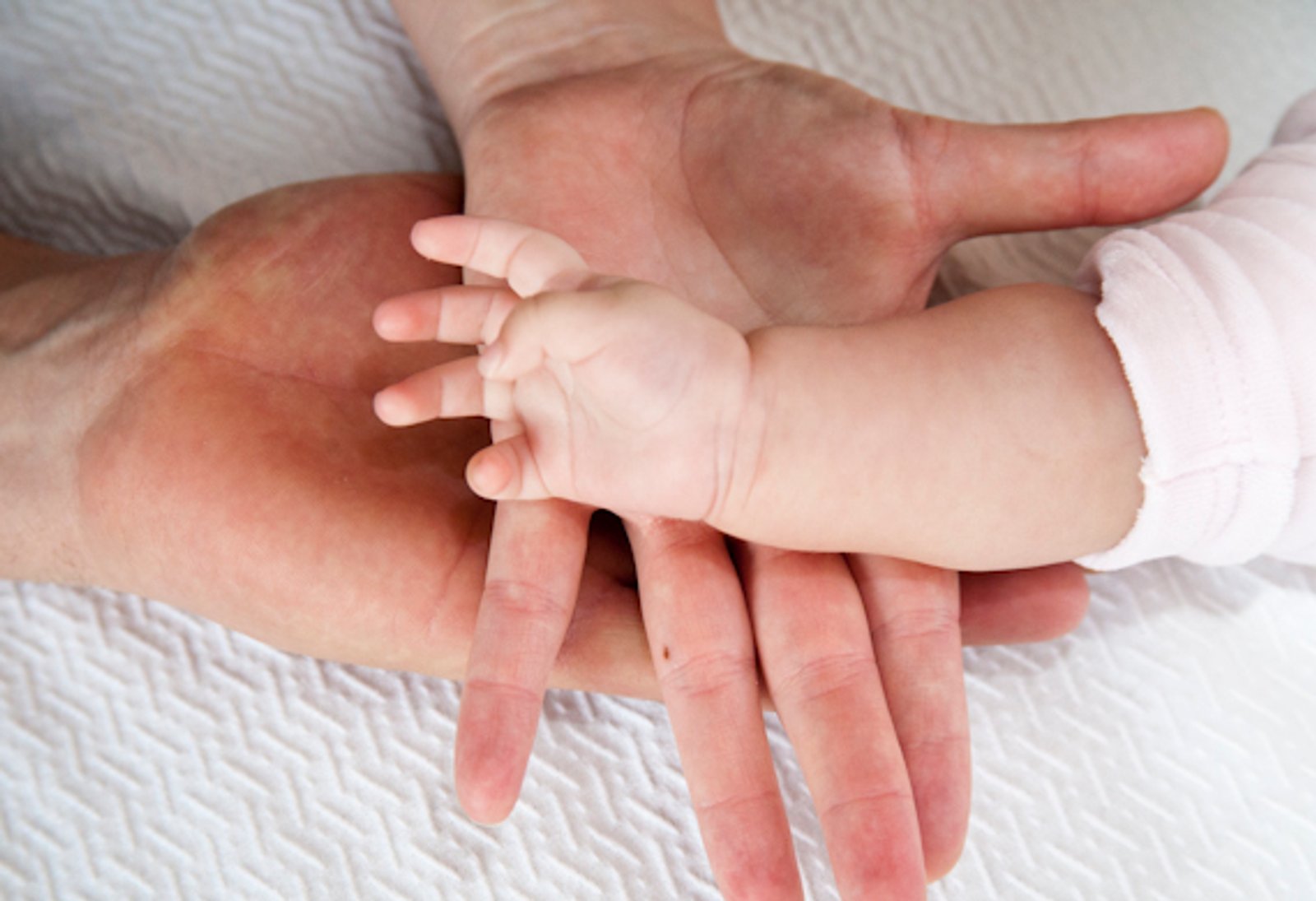 La mano de un bebé sobre la mano de su padre