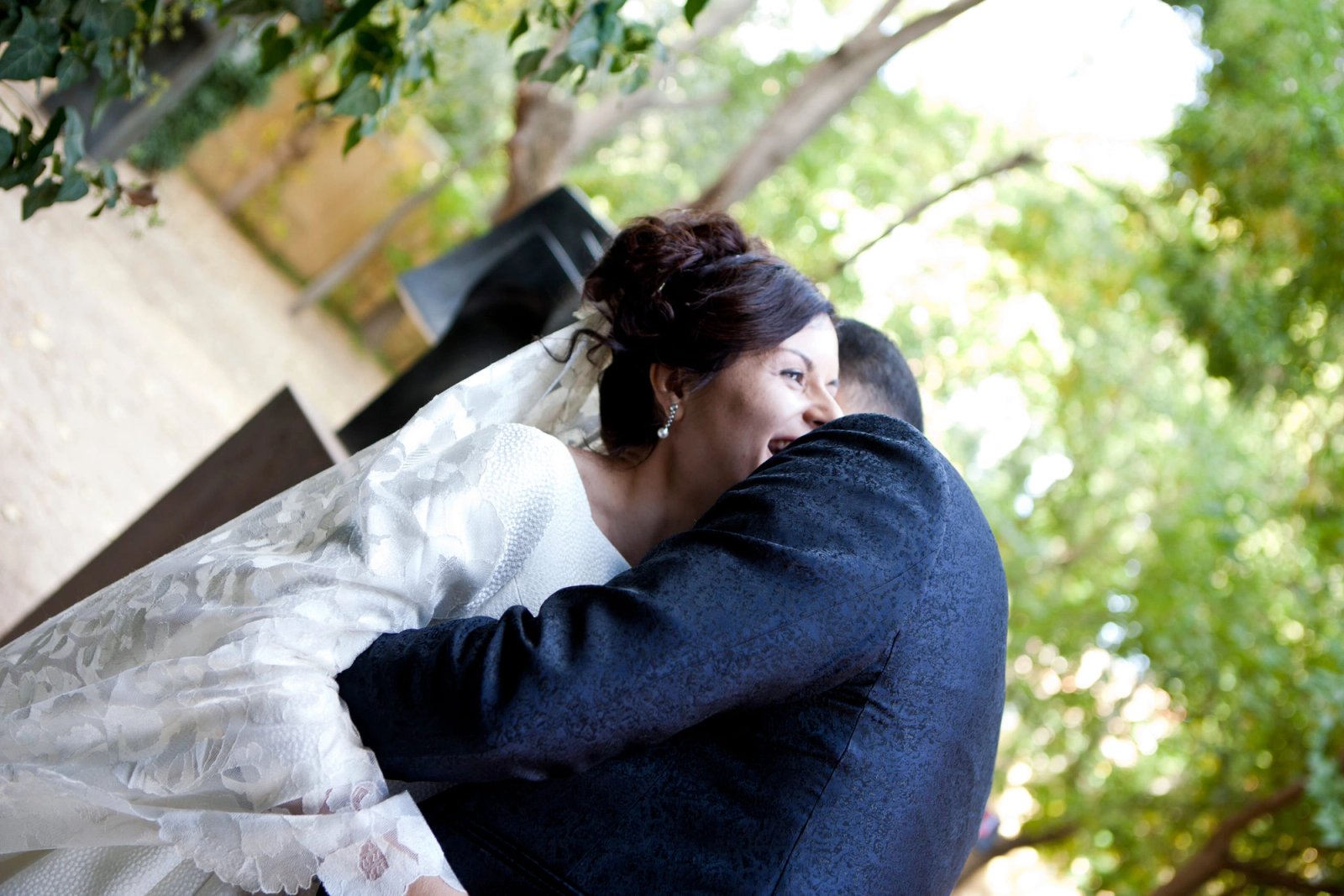 La novia abraza al novio bajo los árboles