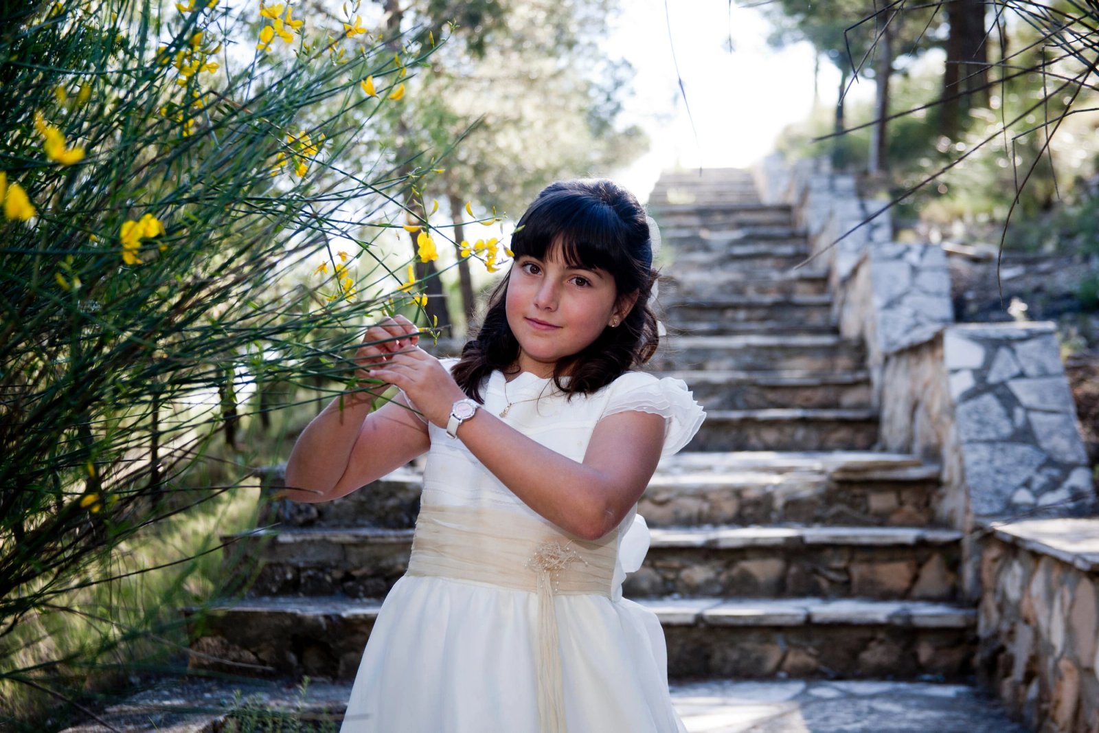 Una niña de comunión al pie de una escalera de piedra