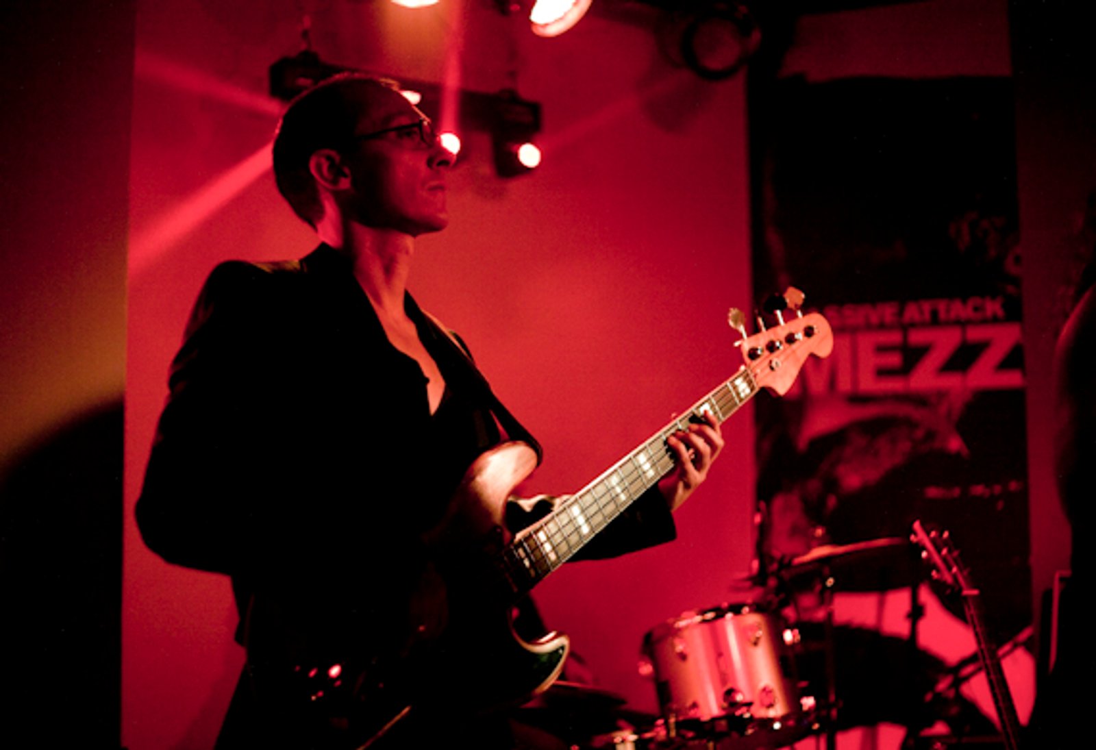 La bajista de una banda bajo las luces rojas del escenario