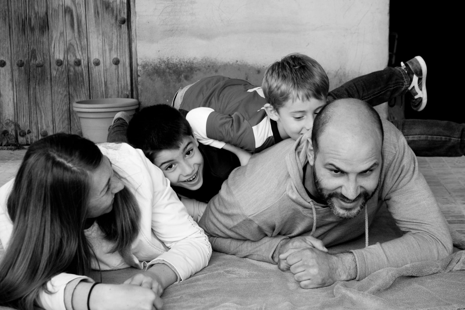 Una familia tumbada en el suelo jugando, en blanco y negro