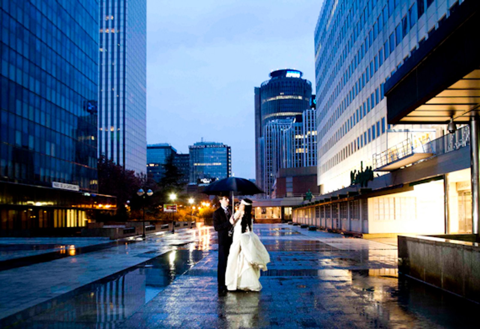 Los novios bajo un paraguas en la ciudad, al anochecer