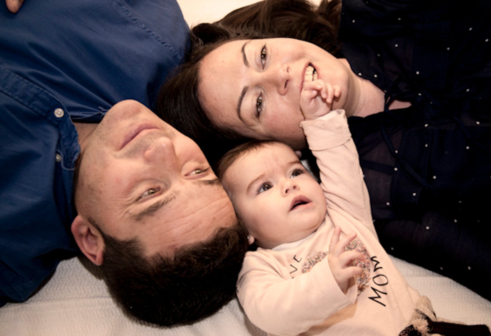 Los padres tumbados con su bebé entre los dos