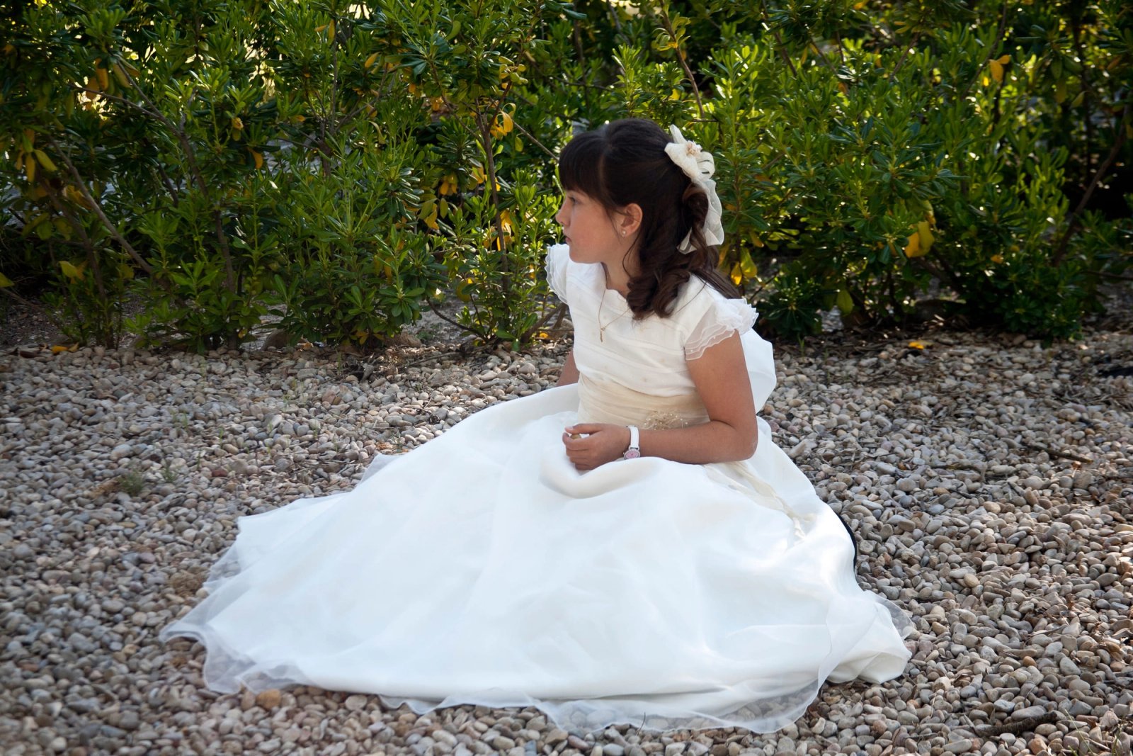 Una niña de comunión sentada en el suelo con el vestido extendido