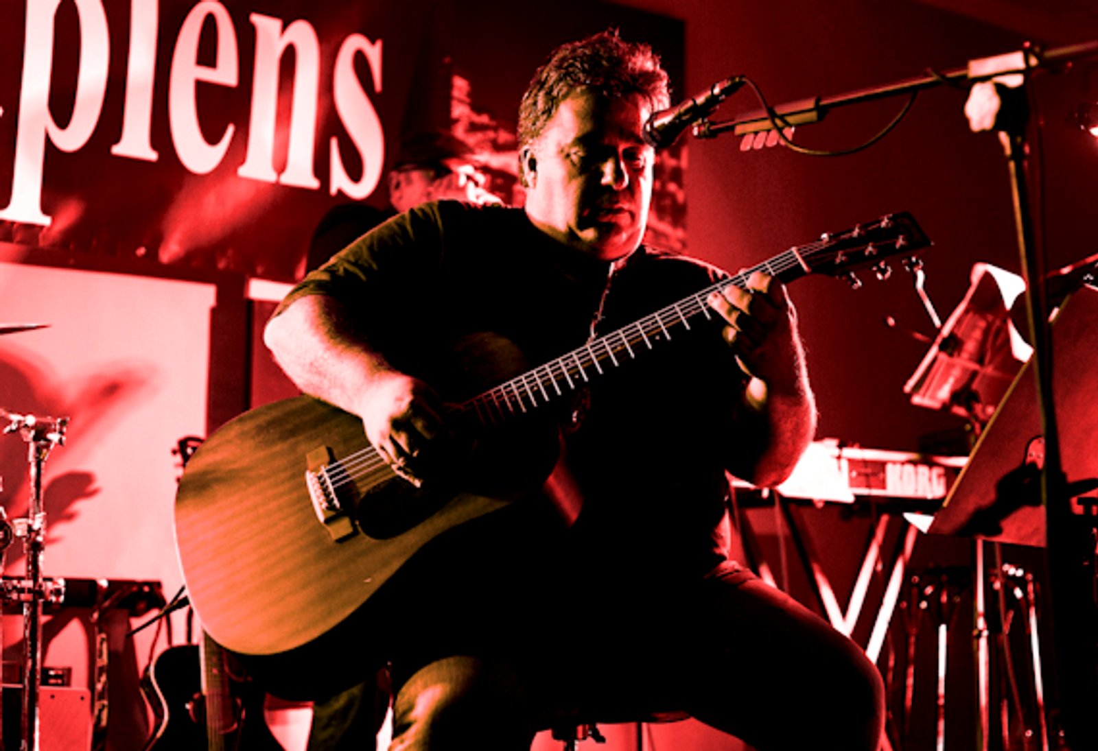 Un guitarrista sentado tocando, bajo luz roja