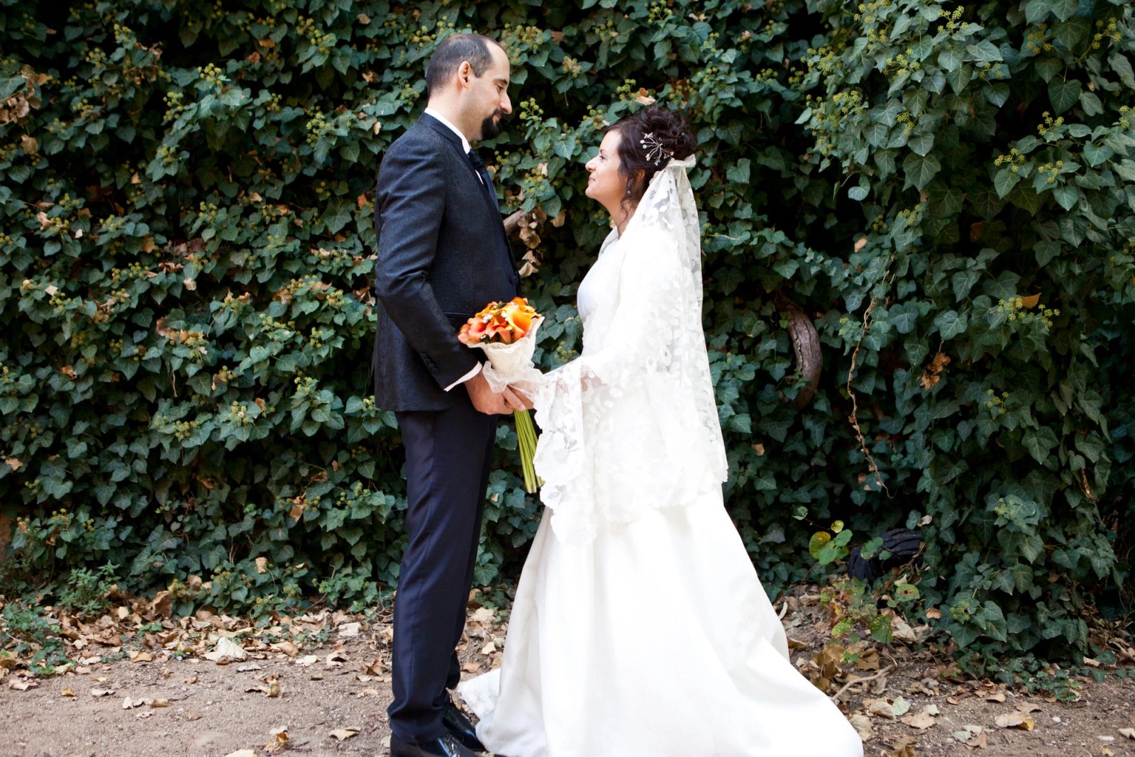 Los novios se miran en un camino entre vegetación