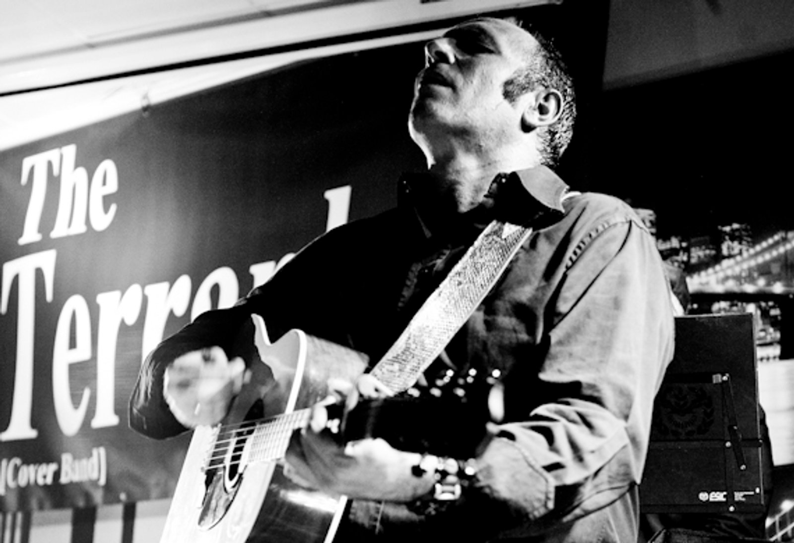 El guitarrista cantando al micrófono, en blanco y negro