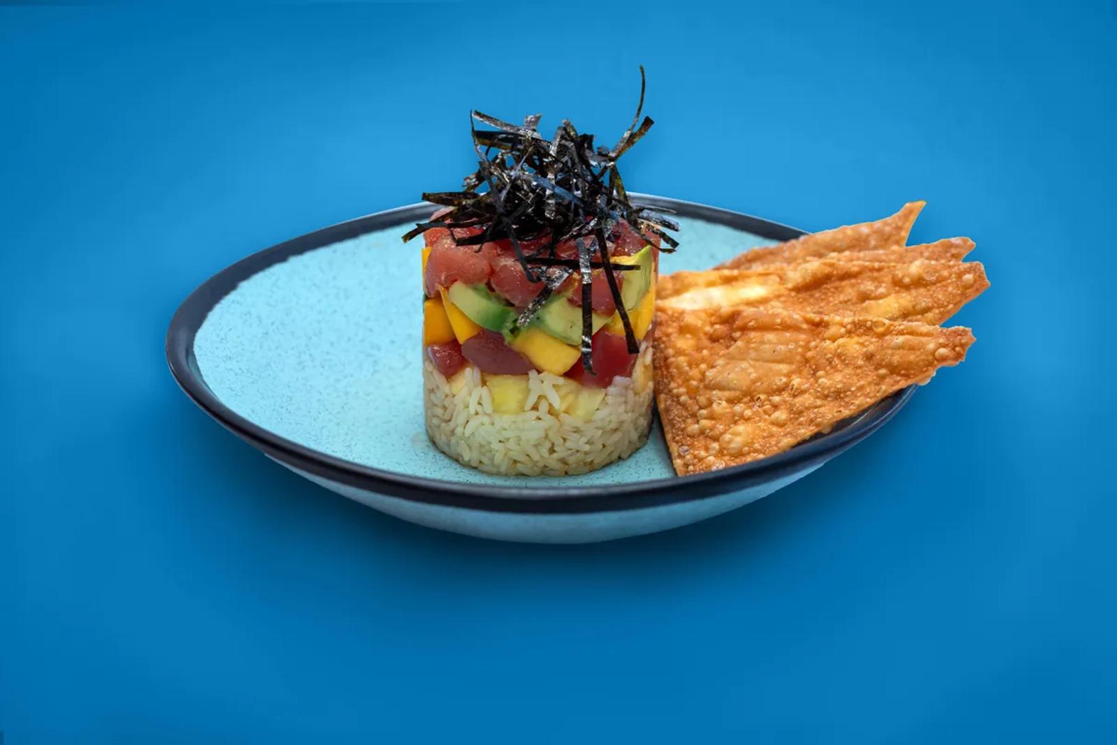 Ahi poke stack with wonton crisps on a blue seamless