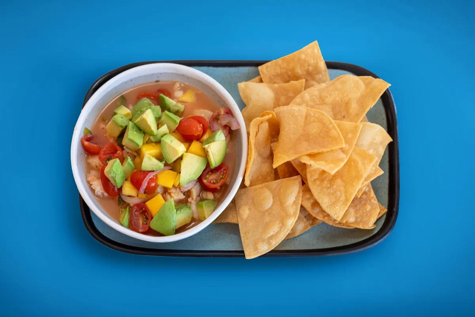 Ceviche plated with tortilla chips on a blue seamless