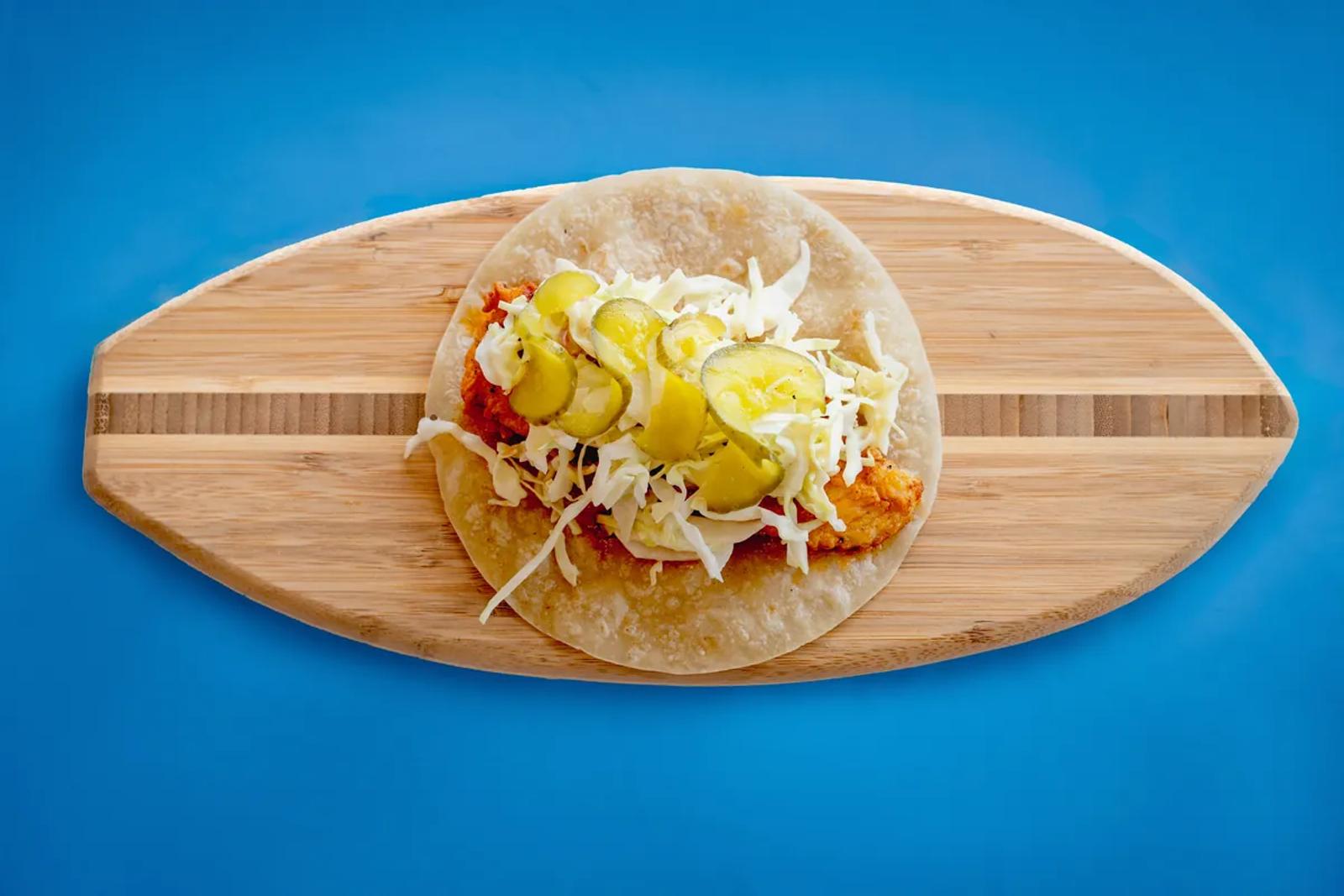 Nashville hot chicken taco on a wooden board