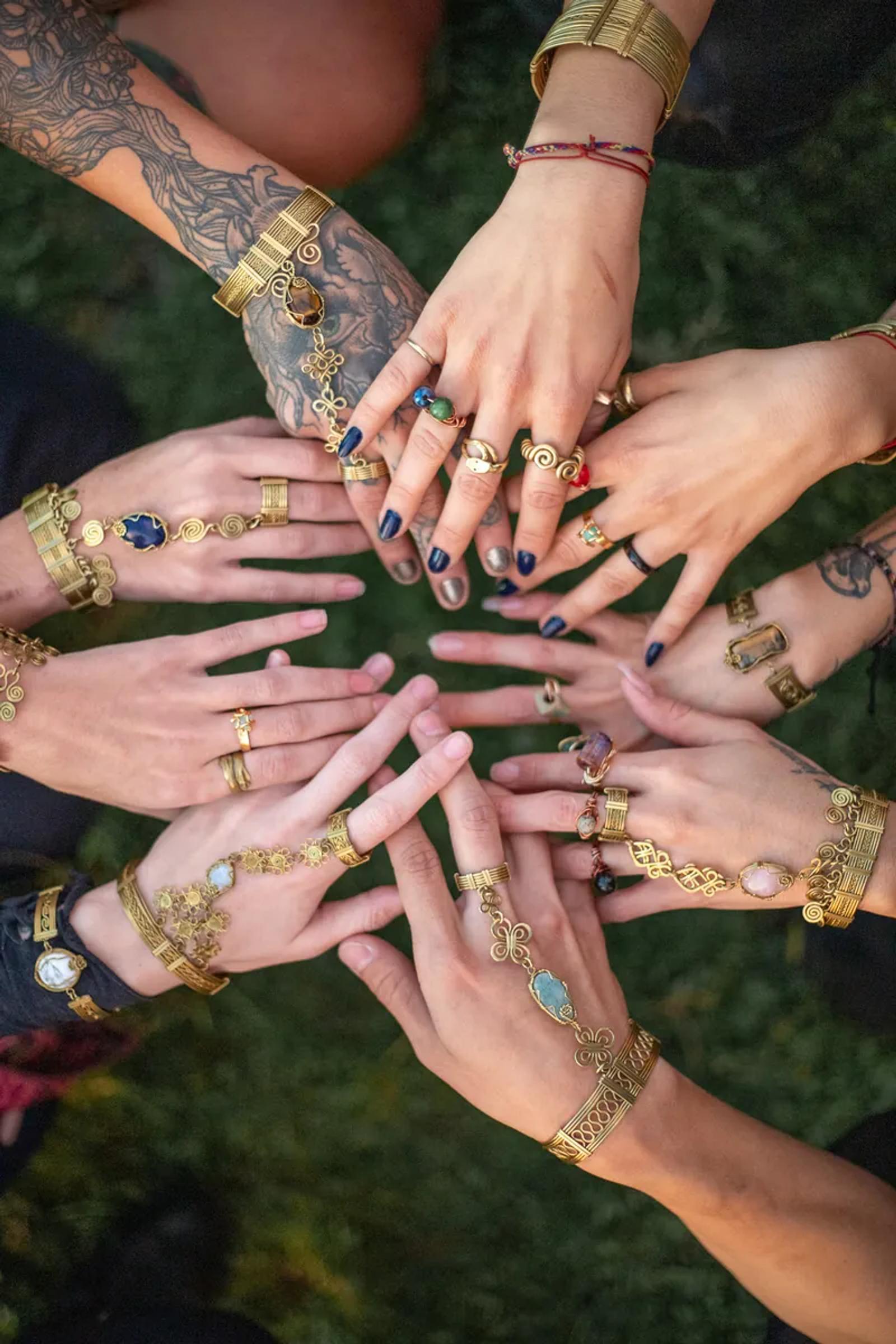 Hands arranged in a circle wearing rings and bracelets