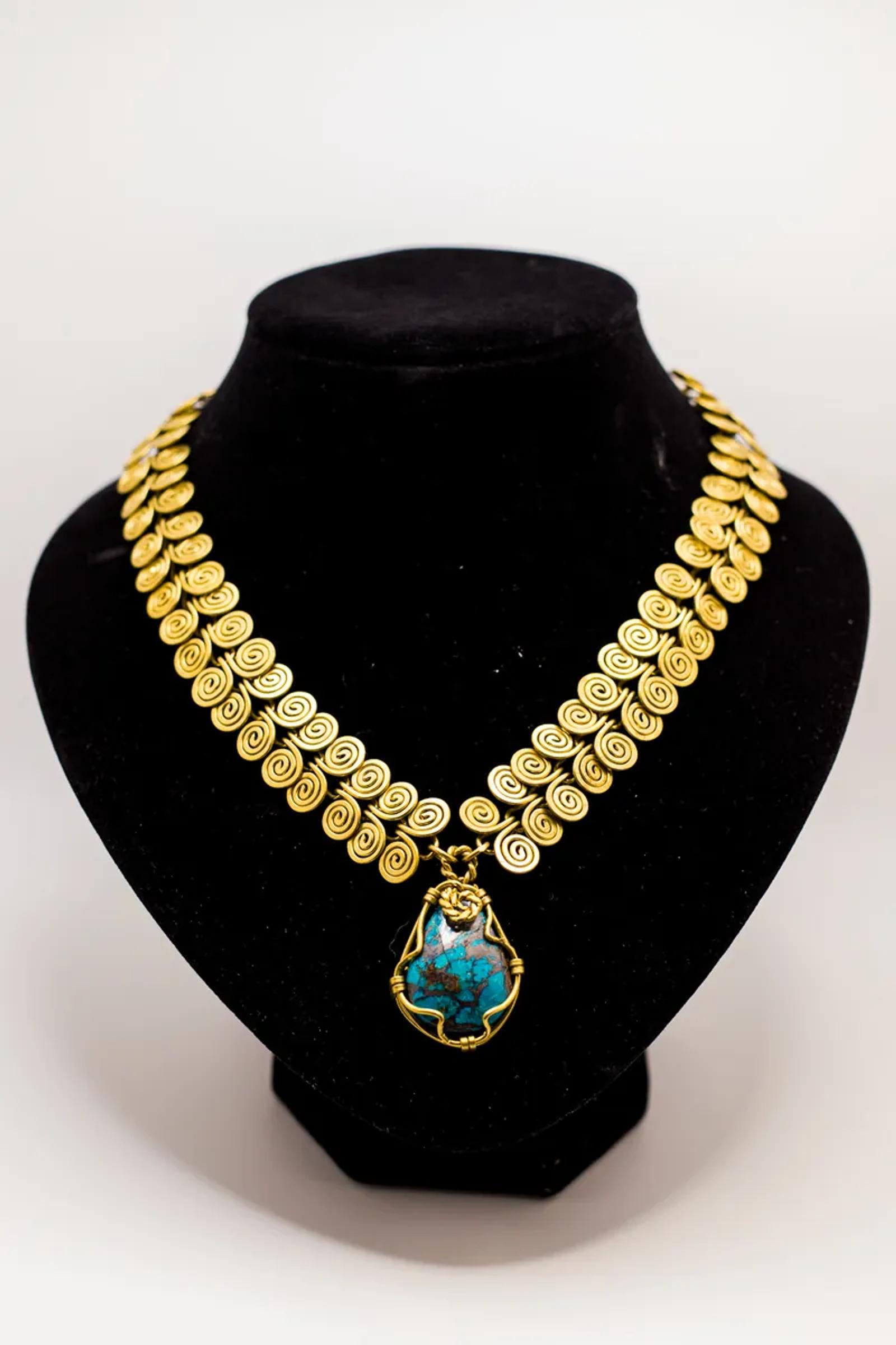 Gold collar necklace with turquoise pendant on a bust