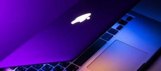 Apple laptop illuminated with blue and purple light