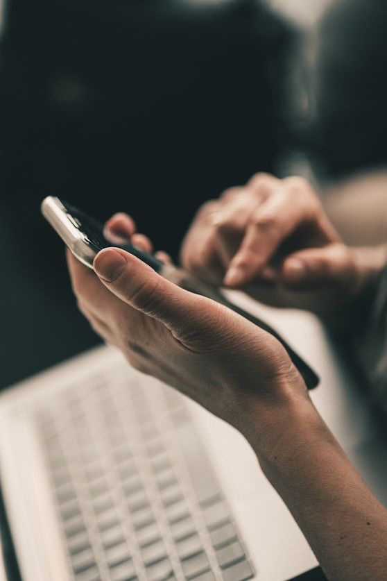 Person using a smartphone beside a laptop