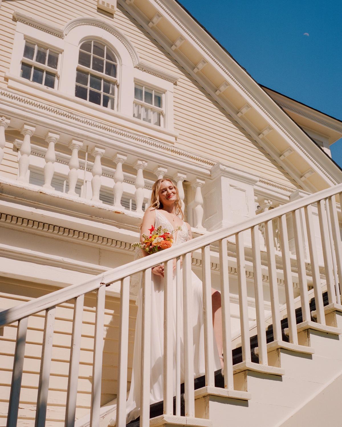 A bride posing for a picture walking up stairs of an coastal lighthouse wedding venue