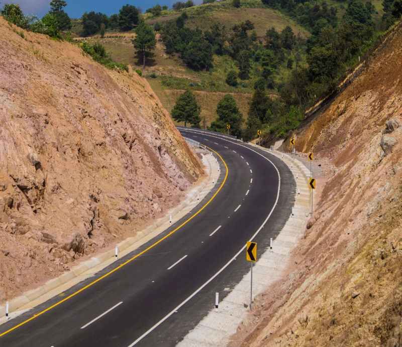 Autopista en curva entre taludes de tierra.