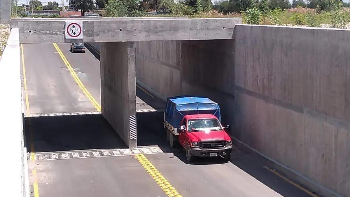 Camión rojo circulando bajo la estructura de concreto del paso Moulinex.
