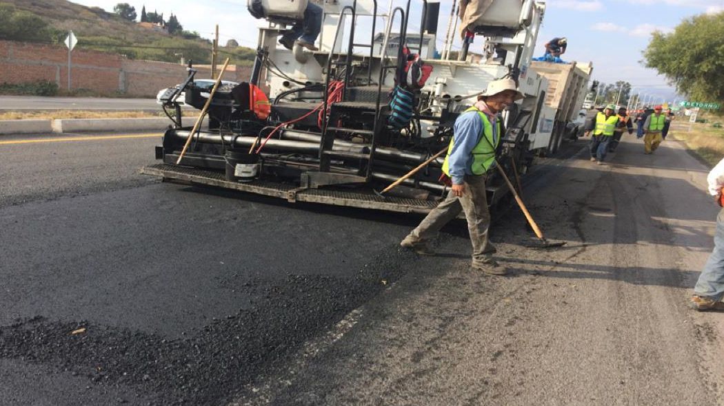 Cuadrilla y pavimentadora extendiendo una capa asfáltica.