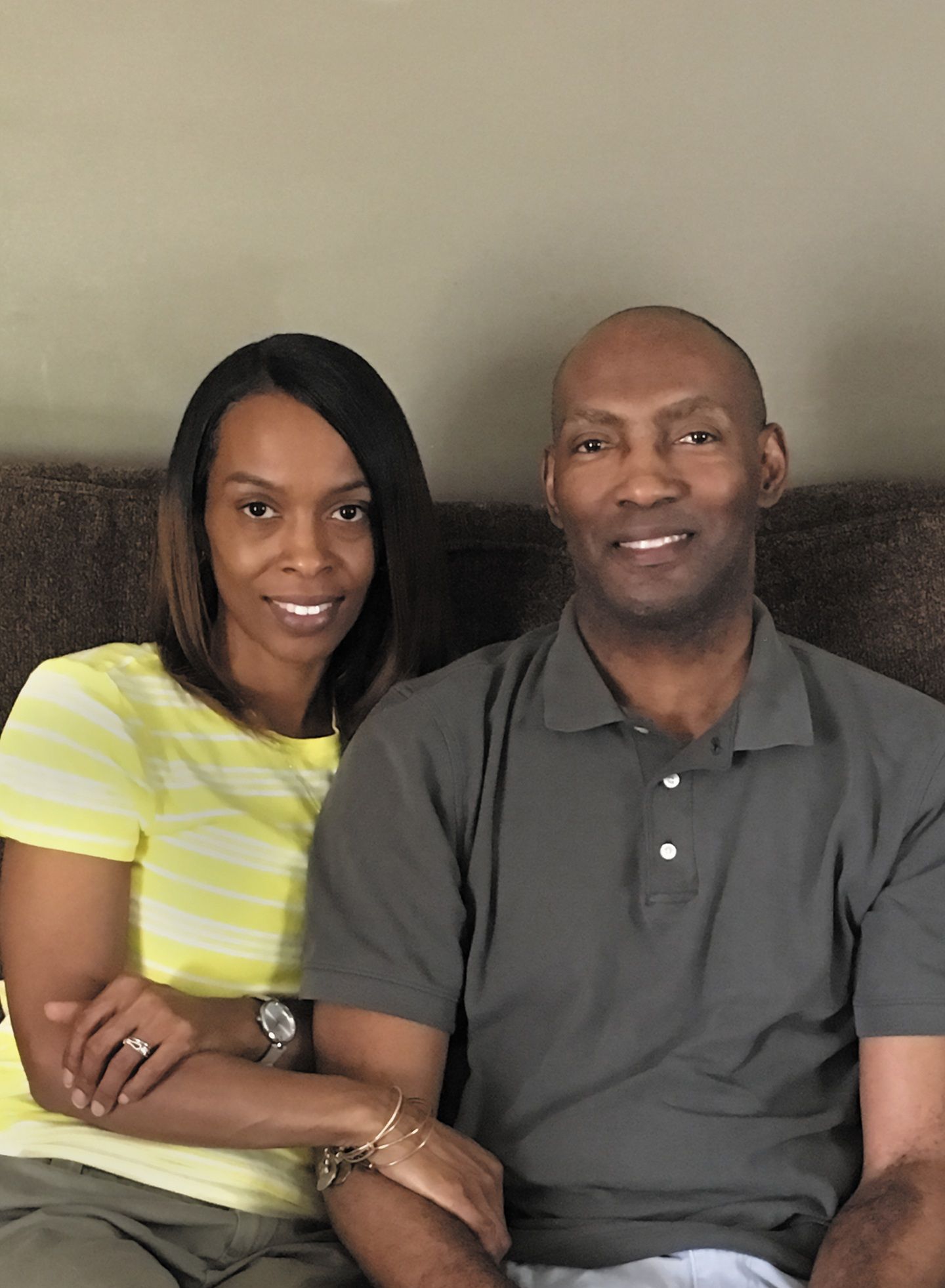 A man and woman relax on a couch, smiling in a cozy living room setting.