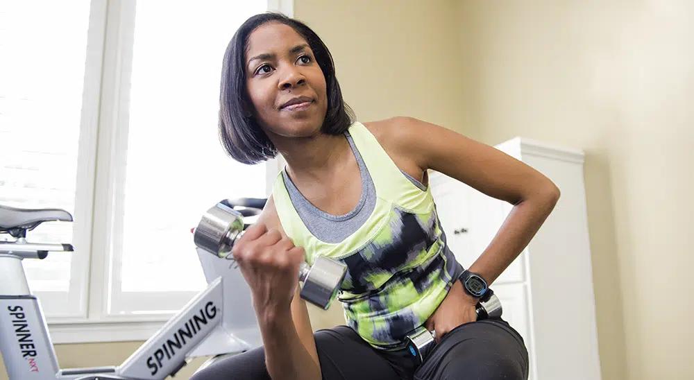 A Black woman lifts weights in a gym