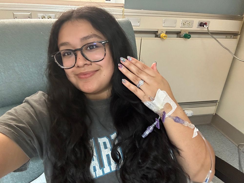 A young woman takes a selfie while getting an infusion treatment.