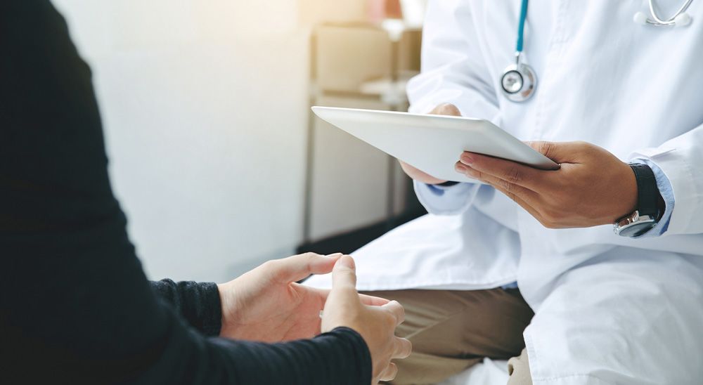 A doctor wearing a lab coat speaks with a patient.