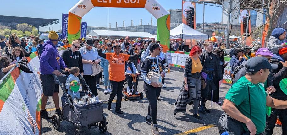 A large crowd of people at Walk MS, a starting arch reading "Let's Go!" behind them.