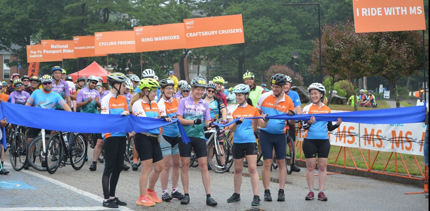 Photo of a group of cyclists at a racing start line at Bike MS, cutting the event ribbon before the event begins.