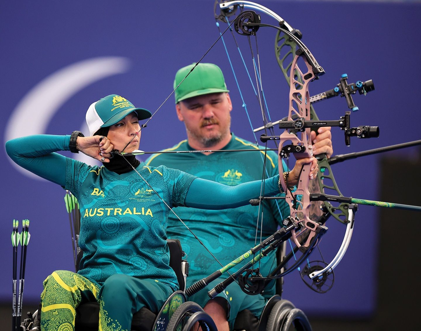 Ameera Lee, seated in a wheelchair, draws her bow with a look of concentration