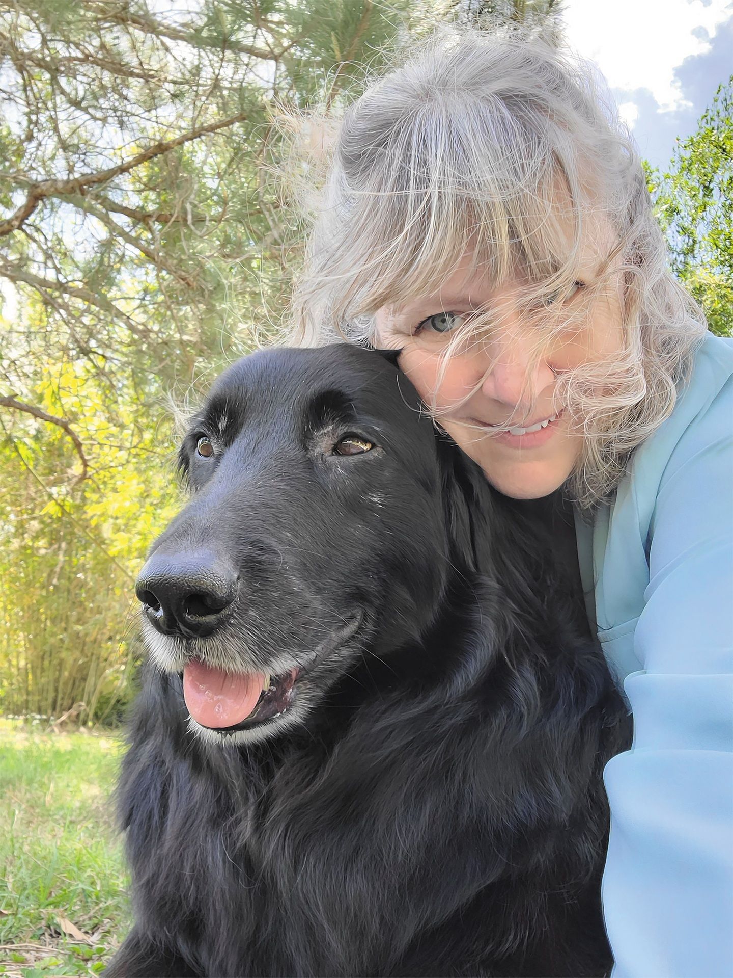 A woman embraces a black dog, highlighting their bond.
