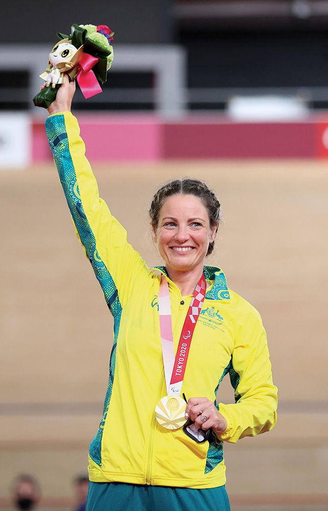 Emily Petricola smiles on the podium, wearing her 2020 gold medal and holding flowers.