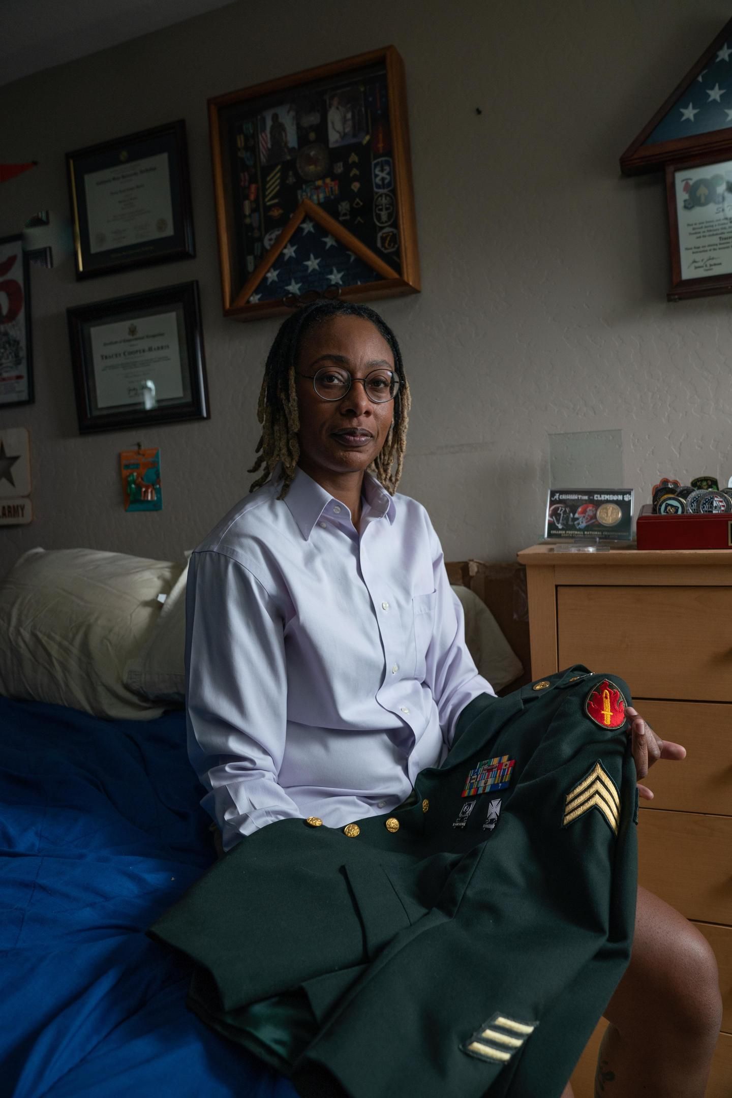 Tracey, a Veteran who lives with MS, sits on her bed with her uniform draped across her lap.