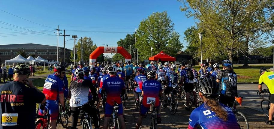 Rear view of a large group of cyclists as they ride through the Bike MS starting arch.