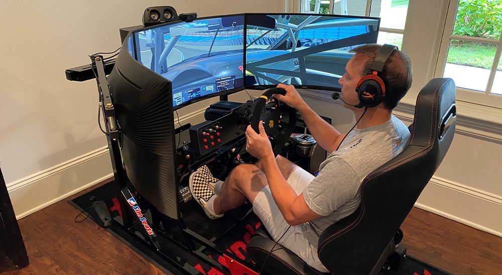 A man in a gray shirt using a driving simulator.