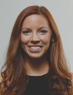 A woman with long red hair in a black shirt smiling at the camera