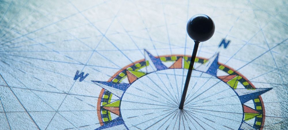 A pushpin in the middle of a compass rose symbolizes pathways