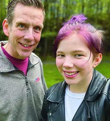 Keven Byrne stands next to his daughter, a teen with short, purple hair.