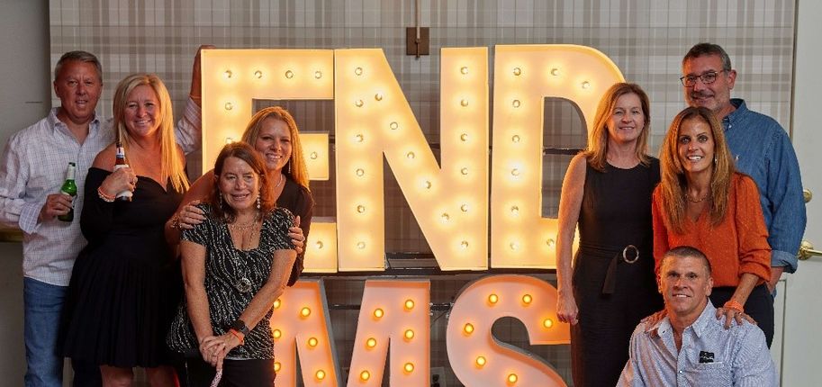 A group of people pose in front of a sign that says “End MS.”