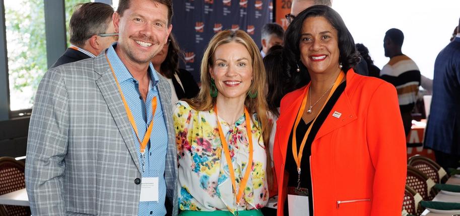 A white man with short hair and mustache, white woman with long blonde hair, and black woman with short hair pose side-by-side for a photo.