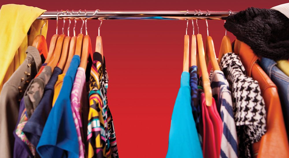 Colorful clothes hang in a closet.